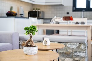 A modern kitchen with a dining area, a potted bonsai tree on a round table, and a stone wall. - Luxury Villa with Private Swimming Pool, BBQ, playground, 5 min. from Prasonisi! (Rhodes)