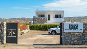 Une villa moderne avec une façade en pierre, un ciel dégagé et un espace de stationnement.
