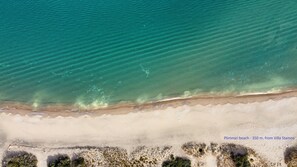 Vista aérea de una playa con agua turquesa cristalina y una orilla arenosa.