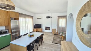 Una cocina moderna con un refrigerador grande, una mesa de comedor y sillas. Hay un televisor y una chimenea en la sala de estar.