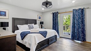 A bedroom with a bed, bedside tables, a ceiling fan, and a view through a glass door to an outdoor area. - Lake Wissota Lookout – A Luxury Escape (Chippewa Falls)