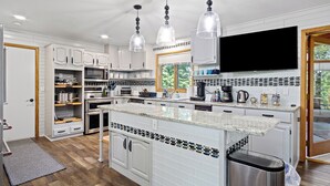 A modern kitchen with white cabinets, a large island, stainless steel appliances, and pendant lighting. - Lake Wissota Lookout – A Luxury Escape (Chippewa Falls)