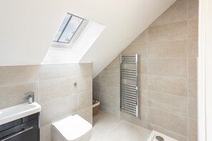 Une salle de bain moderne dotée d’un puits de lumière, d’un lavabo encastré, de toilettes et d’un porte-serviettes.
