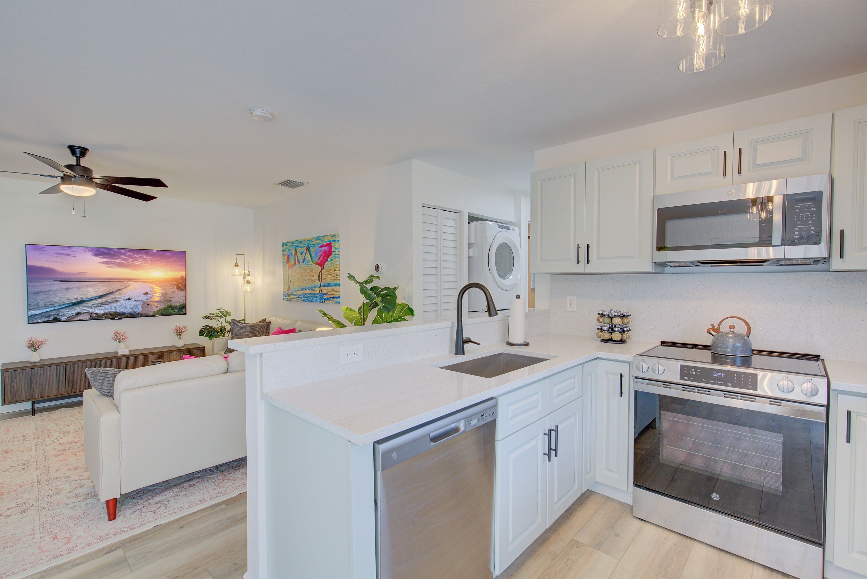 A modern kitchen with a dishwasher, oven, microwave, and a ceiling fan.