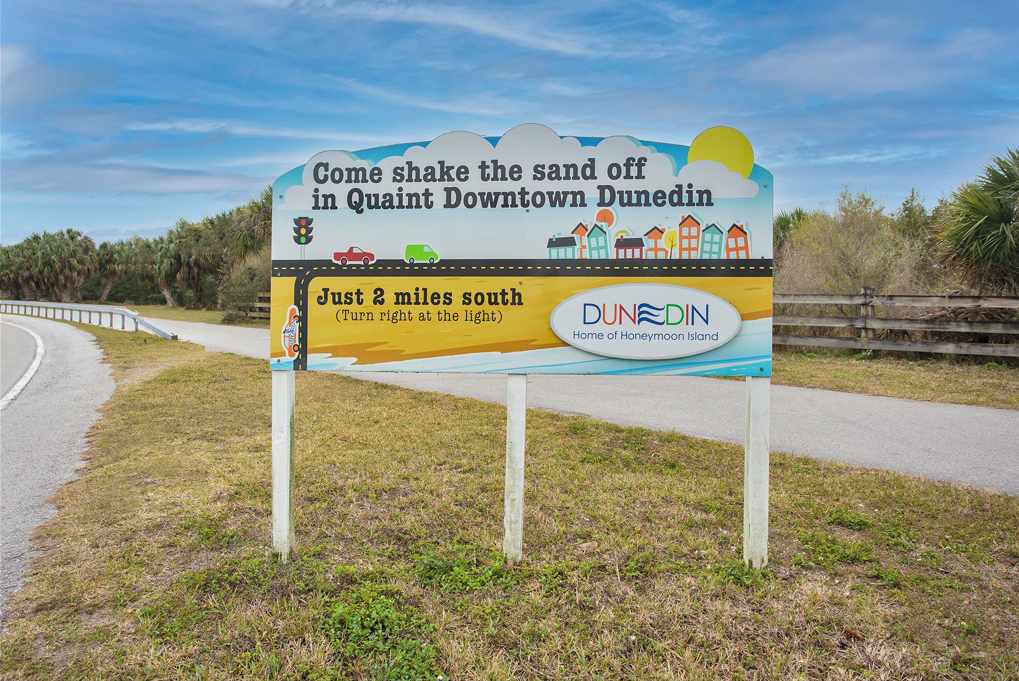 A sign for Quaint Downtown Dunedin advertising a 2-mile drive south to the home of Honeymoon Island.