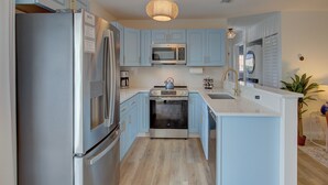 Una cocina moderna con armarios azul claro, electrodomésticos de acero inoxidable y una isla central.