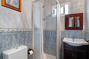 Et badeværelse med toilet, håndvask og bruseområde.