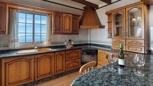 A kitchen with wooden cabinets, a granite countertop, a stove, and a wine bottle. - House Tijoco Bajo 3 bed Room Adeje (Adeje)
