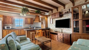 A spacious living area with a large sofa, wooden coffee table, and a television mounted on a brick wall. - House Tijoco Bajo 3 bed Room Adeje (Adeje)