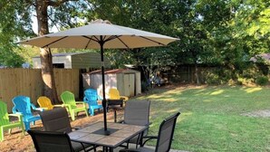 A patio with a table and chairs, an umbrella, and colorful chairs. - Cozy 3-bedroom house in gorgeous Fort Walton Beach with WiFi, AC all amenities  (Fort Walton Beach)