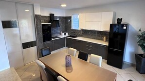 A modern kitchen with black and white cabinetry, a built-in oven, and a refrigerator. - Apartments Lucija & Andora (Kastela)