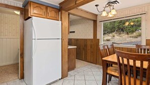 A kitchen with wooden cabinets, a white refrigerator, and a dining area with wooden chairs and a table.
