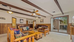 A spacious living room with wooden furniture, a ceiling fan, and a large sliding glass door leading to an outdoor area.