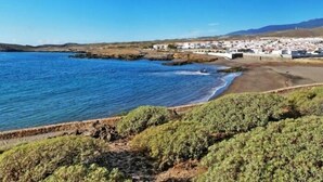 Une zone côtière comprenant une plage, une côte rocheuse et un ensemble de bâtiments blancs.