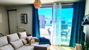 Un salon moderne avec un canapé, une petite table et une plante en pot.