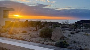 Une maison moderne offrant une vue sur le coucher de soleil sur l’océan.