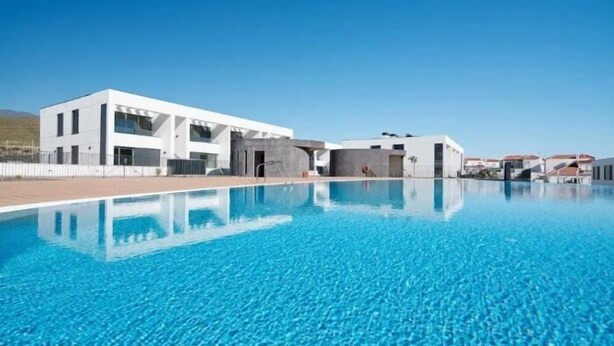 Un hôtel moderne doté d’une piscine, caractérisé par un style architectural contemporain et une eau d’un bleu cristallin.