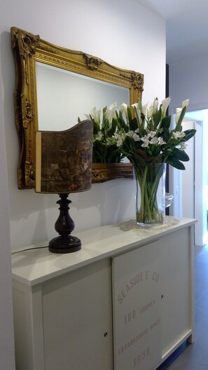 A white console table with a mirror and a vase of white flowers. - OBLO' PORTOVENERE GUESTHOUSE (Portovenere)