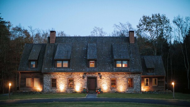 A stone house with a steeply pitched roof and a central entrance.