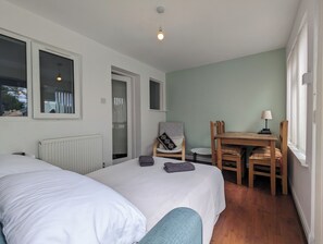 A bedroom with two beds, a chair, a table, and a window. - The Pollard Home | Acocks Green (Birmingham)