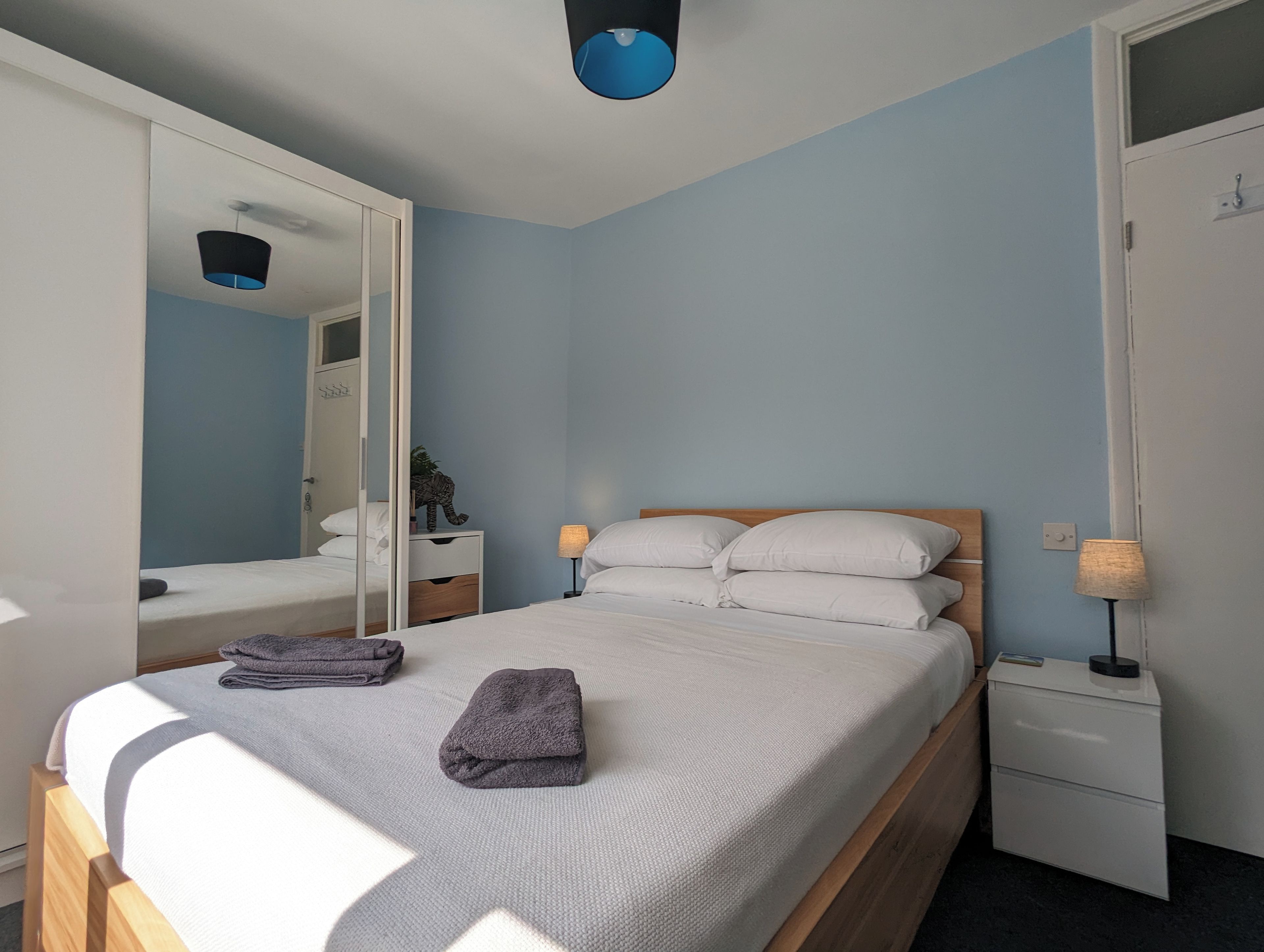 A bedroom with a bed, bedside tables, a wardrobe, and a mirror.