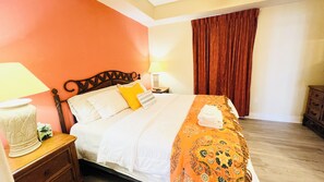 A hotel room with a bed, a nightstand, a lamp, a dresser, and a window with curtains. - Amazing lake view condo with fantastic Disney firework and water sports (Kissimmee)