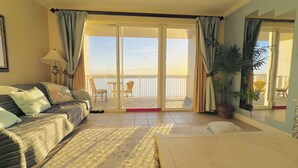 Ein Zimmer mit einer Couch, einem kleinen Tisch, einem Stuhl und einem Balkon mit Meerblick.