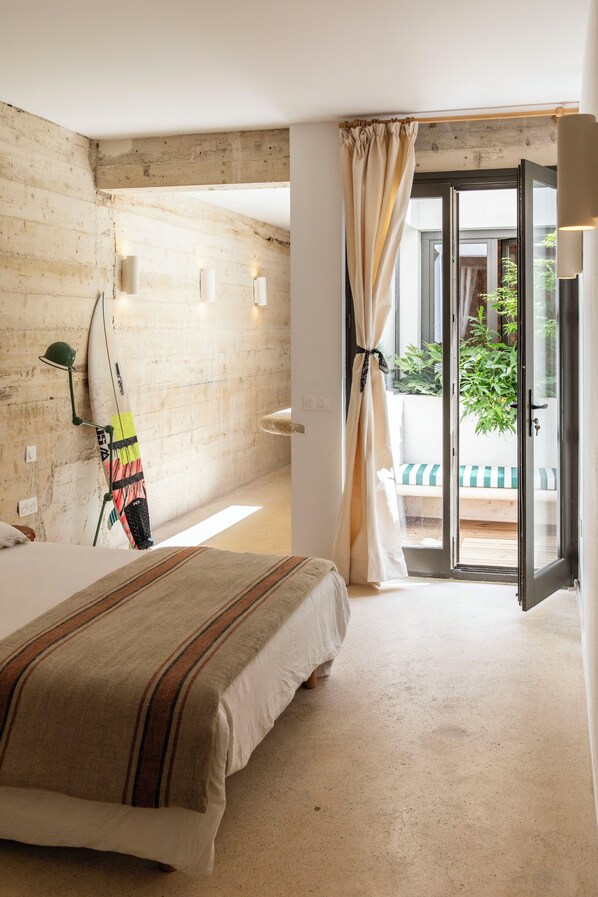 A bedroom with a bed, a surfboard, a curtain, and a view of the outdoors. - Granite house, right on the water, Malmousque (Marseille)