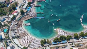 An aerial view of a coastal area with a beach, boats, and a pier. - Vila Sefedin (Ksamil)