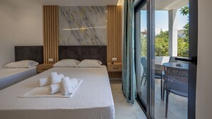 A modern hotel room with a large bed, a wooden headboard, a marble wall, and a balcony with a table and chairs. - Vila Sefedin (Ksamil)
