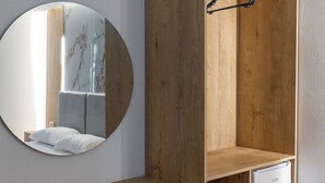 A compact room with a wooden wardrobe, a small white refrigerator, a round mirror, and a wooden shelf with drawers. - Vila Sefedin (Ksamil)