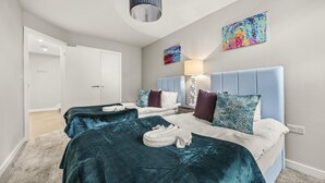 Ein Hotelzimmer mit zwei Betten, einem großen Fenster, einer Deckenleuchte und einem Gemälde an der Wand.