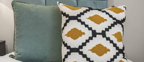 A bed with two pillows, one plain and one patterned.