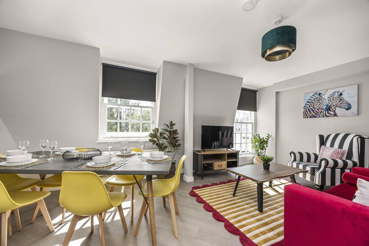 A modern living room with a dining area, a striped sofa, and a television.