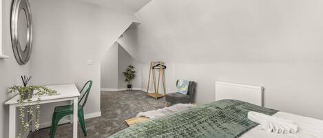 Ein Schlafzimmer mit Bett, Schreibtisch, Stuhl und Heizkörper.