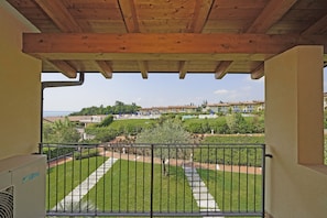 A balcony with a view of a landscaped garden and residential buildings. - Montecolo Resort E7 by Wonderful Italy (Manerba del Garda)
