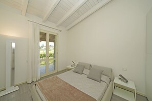 Une chambre à coucher avec un lit, une table de chevet, une fenêtre avec des rideaux et une vue sur un balcon.