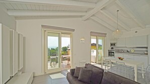 A modern living area with a sofa, dining table, and kitchen. - Montecolo Resort E7 by Wonderful Italy (Manerba del Garda)