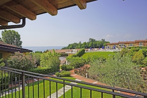 A residential area with a view of the sea, a paved pathway, and a well-maintained lawn.