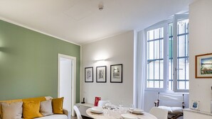 A room with a green wall, a white door, a dining table set with plates and glasses, and a window with blinds. - Brignole Refined Home by Wonderful Italy (Genova)