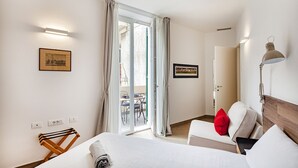 A hotel room with a bed, a desk, a chair, a lamp, and a sliding glass door leading to an outdoor area. - Brignole Refined Home by Wonderful Italy (Genova)