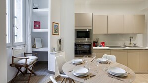 A modern kitchen with a dining area, including a table set for four, a microwave, and a sink. - Brignole Refined Home by Wonderful Italy (Genova)