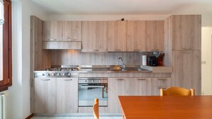 Una cocina moderna con armarios de madera, estufa, horno y una mesa de comedor con sillas.
