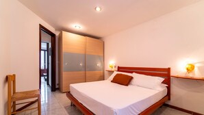 Un dormitorio con cama de madera, una silla y un armario.