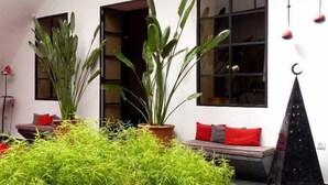 A room with a large window, a black triangular decoration, and a potted plant. - Riad La Parenthese (Marrakech)