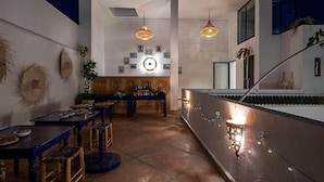 An open-plan living area with a dining table, chairs, and a kitchen counter. - Riad La Parenthese (Marrakech)