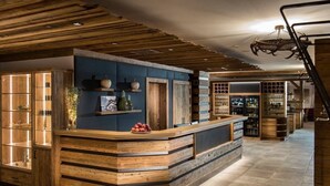 A rustic bar area with wooden accents, a counter, and shelves with decorative items. - Hotel Sendlhof (Waidring)