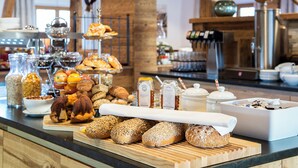 A buffet with various breads, pastries, and condiments. - Hotel Sendlhof (Waidring)