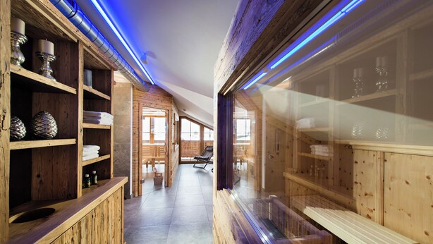 A wooden spa area with shelves, benches, and a glass partition. - Hotel Sendlhof (Waidring)