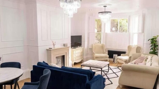 A living room with a fireplace, a television, a dining table with chairs, and a sofa. - Stunning Victorian apartment with garden (London)